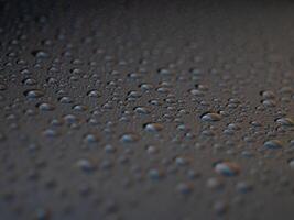 A black surface with many small drops of water on it photo