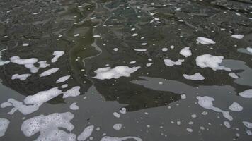 A closeup view of intricate bubbles and frothy foam on dark water, showcasing a beautiful, smooth reflection video