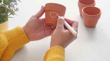 Creative handpainting on terracotta pot with heart design in bright studio setting video