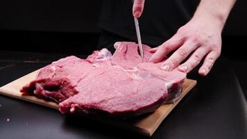A man prepares a large beef steak before roasting. He makes cuts for marinating. video