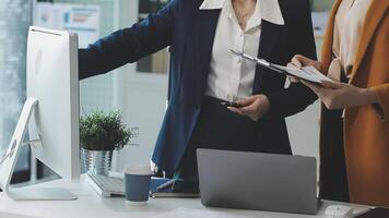 Two businesswomen are standing in front of a computer video
