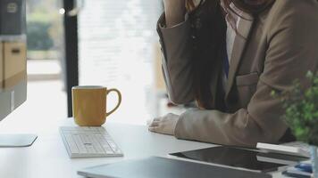 A woman in a business suit sitting at a desk with a computer and a coffee cup video