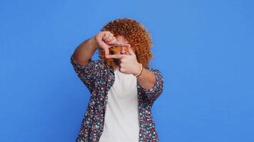 Man photographer gesturing picture frame with hands, looks through fingers focusing cropping image video