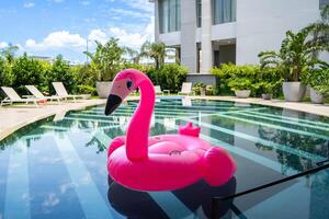 A pink flamingo pool float is floating in a pool. photo