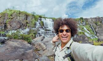 exultant traveler takes selfie with waterfall in the background photo