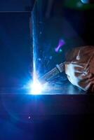 Unrecognizable welder using welding machine in darkness photo