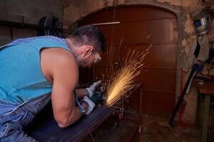 Man cutting metal standing at workbench and using disk grinder photo