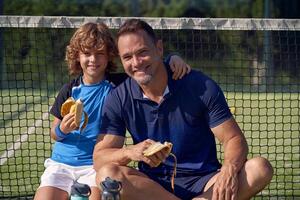 Smiling boy and trainer with bananas on court photo