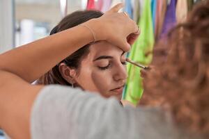 Unrecognizable woman applying eyeshadow on model photo