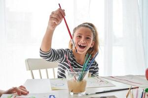Cheerful girl with paintbrush at table photo
