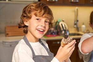 Smiling boy with homemade cupcake in paper baking tin photo