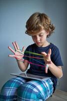 Focused boy browsing tablet while playing string game photo