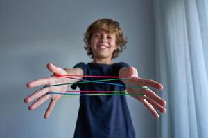 Smiling boy making string figures photo