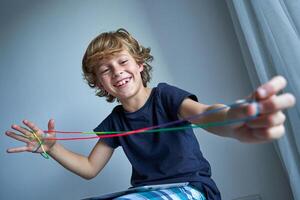 Cheerful boy playing string game in living room photo