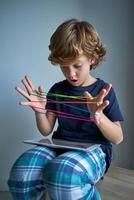 Astonished boy playing string game with tablet photo