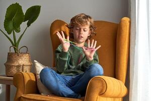 Focused boy wrapping colourful string around fingers photo
