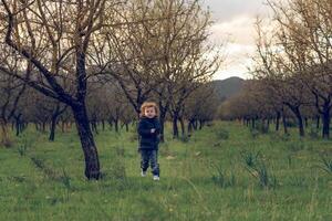 Boy running in grove with trees photo
