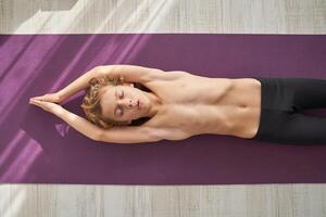 Calm kid lying on mat in banana pose photo