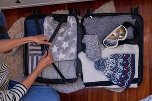Anonymous traveler with opened packed baggage on floor photo