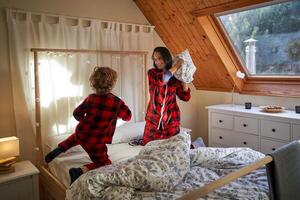 Positive mom tossing soft pillow while playing with son photo