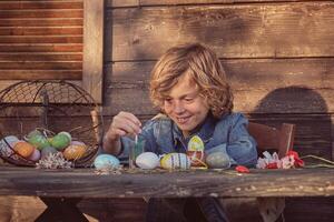 Little smiling boy with Easter eggs and paints photo