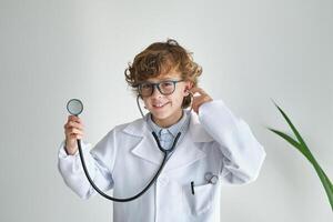 Smiling boy in medical uniform with stethoscope on white backgro photo