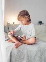 Focused boy sitting on soft plaid and browsing tablet photo