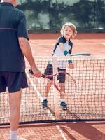 Active little boy practicing tennis with crop male instructor photo