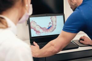Unrecognizable dentists examining 3D teeth scan photo