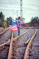 Delightful child having stroll on rails with flag of America photo