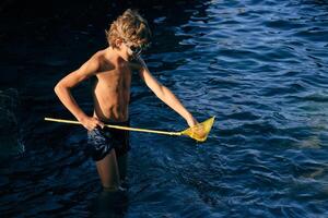Shirtless boy with net in wavy ocean photo
