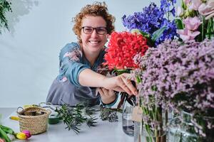Smiling woman with blooming flowers in floral store photo
