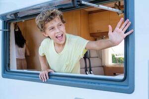 Happy boy waving hand from RV window photo