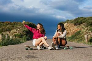 Cheerful multiethnic friends on longboards taking selfie on smartphone photo