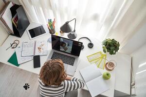Unrecognizable boy chatting on laptop while studying photo