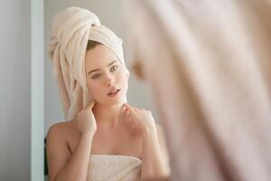Serene woman in towel looking in mirror photo