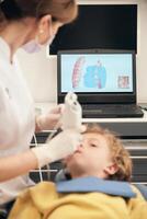 Unrecognizable dentist making 3D teeth scanning of boy photo