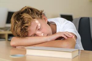 Pupil sleeping on table in classroom photo