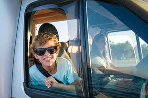 Delighted kid enjoying road trip in summertime photo