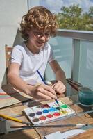 Smiling kid painting with watercolor paints photo