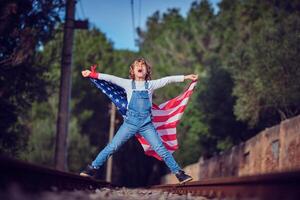 Excited boy with American flag on railway photo