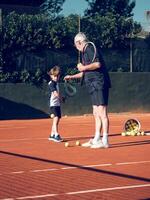 Senior trainer explaining preteen boy with tennis racket techniq photo