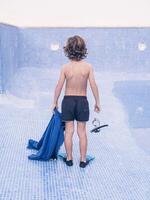 Preteen boy in flippers with diving mask on empty pool photo
