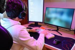 Anonymous young man in headphones playing on keyboard and sitting at table with gadgets photo