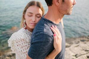 Young woman hugging man on wild beach photo