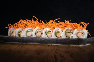 Row of sushi maki with salmon decorated with shredded carrot served on plate photo