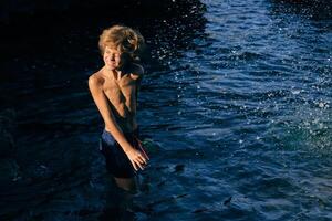 Boy grimacing in wavy sea with splashing water photo