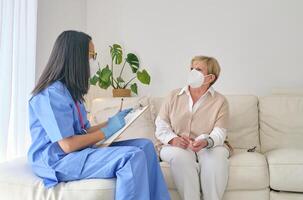 Anonymous doctor speaking with patient in respiratory mask at ho photo