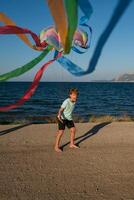 Excited kid with flying kite on beach photo