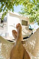 Crop man resting in hammock near RV photo